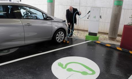 (FILES) In this file photo taken on March 17, 2014 a man plugs his car in Paris, at the charging station for electric vehicles dedicated to public services staff at the French economic and financial ministries after its inauguration. - With summer holidays looming, Europe's electric car owners may be wondering whether to risk taking their vehicles for long journeys. AFP investigates the pitfalls and joys of long-distance emissions-free motoring. (Photo by Jacques DEMARTHON / AFP)