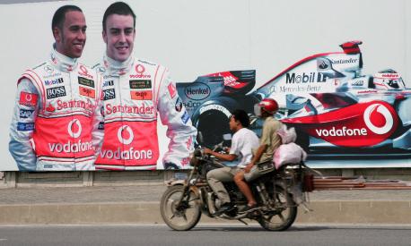 epa01138288 A motorbike passes in front of a giant poster of Spanish Formula One driver Fernando Alonso and his British teammate Lewis Hamilton of McLaren Mercedes 04 October 2007 in Shanghai, China. The Chinese Formula One Grand Prix will take place at Shanghai International Circuit 05 October 2007.  EPA/GERO BRELOER BASIS