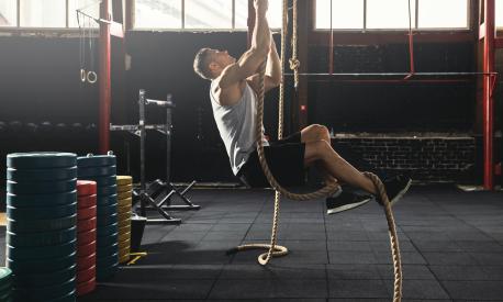 Rope climbing exercise. Sportsman during his cross training workout