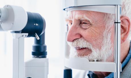 Cropped photo of happy senior patient being diagnosed with ophthalmic equipment