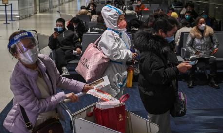 A passenger wearing protective clothing amid the Covid-19 pandemic waits to board a domestic flight at Shanghai Pudong International Airport in Shanghai on January 3, 2023. (Photo by HECTOR RETAMAL / AFP)