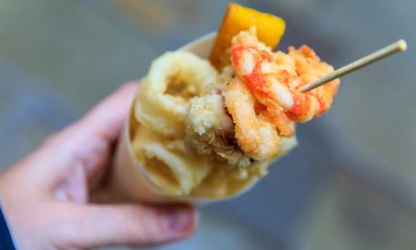 Italian street food in Venice - fritto misto (mix of fried fish, calamari or squid and shrimp) in a cone on the go