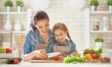 Healthy food at home. Happy family in the kitchen. Mother and child daughter are preparing the vegetables and fruit.