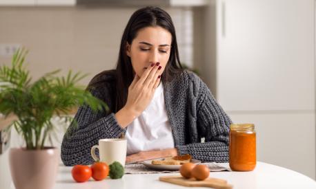 Young woman feeling nausea during breakfast time at home