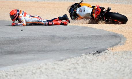 TOPSHOT - Honda Spanish rider Marc Marquez falls after crashing with Aprilia Portuguese rider Miguel Oliveira (out of frame) during the MotoGP race of the Portuguese Grand Prix at the Algarve International Circuit in Portimao, on March 26, 2023. (Photo by PATRICIA DE MELO MOREIRA / AFP)