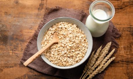 Dry oat flakes, oatmeal, rolled oats and bottle of oat milk on a wooden background. Healthy vegan, vegetarian food. Clean eating, dieting, weight loss concept