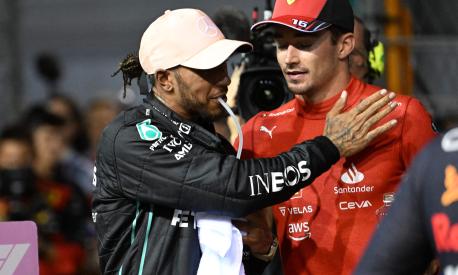 Mercedes' British driver Lewis Hamilton (L) greets Ferrari's Monegasque driver Charles Leclerc (R) after the qualifying session ahead of the Formula One Singapore Grand Prix night race at the Marina Bay Street Circuit in Singapore on October 1, 2022. (Photo by ROSLAN RAHMAN / AFP)