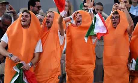 Fans of Italy's Jannik Sinner, dressed as carrots, gestures during his men's singles match against France's Alexandre Muller on day two of the Roland-Garros Open tennis tournament at the Court Philippe-Chatrier in Paris on May 29, 2023. (Photo by Emmanuel DUNAND / AFP)