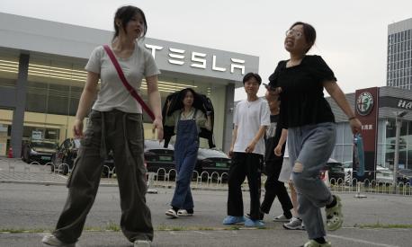 Young Chinese walk past a Tesla showroom in Beijing, Tuesday, May 30, 2023. China?s foreign minister met Tesla Ltd. CEO Elon Musk on Tuesday and said strained U.S.-Chinese relations require ?mutual respect,? while delivering a message of reassurance that foreign companies are welcome. (AP Photo/Ng Han Guan)