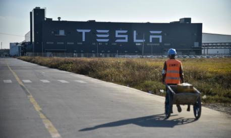(FILES) A worker walks on a road next to the new Tesla factory in Shanghai on November 8, 2019. Tesla's Elon Musk met China's foreign minister Qin Gang in Beijing on May 30, 2023, the Chinese ministry said in a statement. (Photo by HECTOR RETAMAL / AFP)