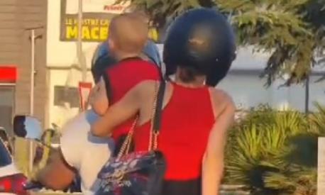 In tre in scooter, bambino in mezzo e senza casco