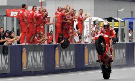 Australian rider Casey Stoner of Ducati wheelies past team members  as he celebrates his race victory of the Malaysian Motocycle Grand Prix at the Sepang racing circuit on October 25, 2009. Meanwhile defending world champion Valentino Rossi claimed his seventh MotoGP title in wet track conditions. AFP PHOTO/ROSLAN RAHMAN