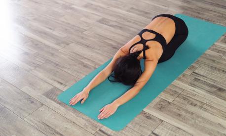 Woman practicing yoga, resting in child pose on the yoga mat. Copy space. Top side view