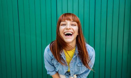 Young beautiful caucasian red hair woman laughing at the camera - Portrait green background