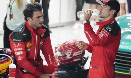 Ferrari driver Carlos Sainz, left, talks while teammate Charles Leclerc drinks after the qualifying session of the Singapore Formula One Grand Prix at the Marina Bay circuit, Singapore, Saturday, Sept. 16, 2023. Sainz took pole position while Leclerc is third. (AP Photo/Vincent Thian)