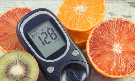 Glucometer with result of sugar level and fresh natural fruits. Diabetes and healthy lifestyle and nutrition
