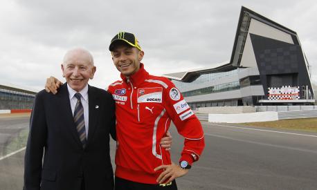 FILE - This is a Tuesday, May 17, 2011 file photo of former British Formula One and Motorcycle world champion John Surtees with former Moto GP world champion Valentino Rossi as they pose for the cameras as the the new pit lane complex at Silverstone race track is opened at Silverstone England.  Surtees, the only man to win world titles on both two and four wheels, has died aged 83, his family said Friday.  Surtees won the Formula One title in 1964 to add to his 500cc motorcycle world titles from 1956, 1958, 1959 and 1960.  (AP Photo/Alastair Grant, file)