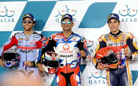 (L to R) Second-place Gresini Racing MotoGP team's Italian rider Enea Bastianini, first-place Pramac Racing's Spanish rider Jorge Martin, and third-place Repsol Honda Team's Spanish rider Marc Marquez celebrate on the podium following the second qualifying session ahead of the Moto GP Grand Prix of Qatar at the Lusail International Circuit, in the city of Lusail on March 5, 2022. (Photo by DENOUR / AFP)