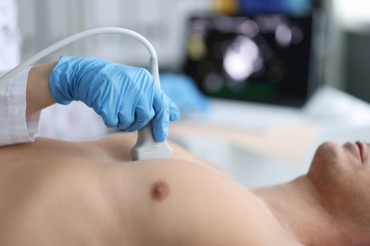 Doctor performs chest ultrasound on man in hospital room. Examination of the heart and vessels concept