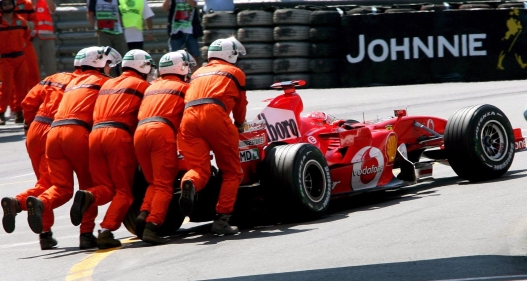 epa00724107 El pilot alemany de Fórmula 1 Michael Schumacher de l'escuderia Ferrari és empès pels comissaris després d'aturar el seu cotxe durant la sessió de classificació a Mònaco el dissabte 27 de maig de 2006. El Gran Premi de Mònaco tindrà lloc el diumenge 28 de maig de 2006. EPA/KERIM OTKEN