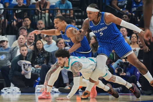 Charlotte Hornets guard LaMelo Ball, center, and Orlando Magic guard Desmond Bane (3) and forward Paolo Banchero (5) go after a loose ball during the first half of an NBA play-in tournament basketball game, Friday, April 17, 2026, in Orlando, Fla. (AP Photo/John Raoux)