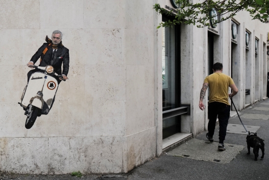 A man walks his dog past a mural by artist Harry Greb depicting the new coach of the AS Roma football team, Jose Mourinho riding a scooter bike, on a wall of a building in the Testaccio district of Rome on May 7, 2021. - For over a decade, hiring Jose Mourinho was a guarantee of instant success, but the new Roma manager's decline has been so steep that he heads to Italy facing a last chance to salvage his tarnished reputation. Mourinho agreed a three-year contract with Roma on May 4, 2021, and will replace their current boss Paulo Fonseca at the end of this season.The 58-year-old was ranked among the world's top managers after winning the Champions League at Porto and Inter Milan, while enjoying domestic glory with Chelsea and Real Madrid. But Mourinho's midas touch has faded in recent years and his last three jobs all ended in the sack at Chelsea, Manchester United and Tottenham.
 - RESTRICTED TO EDITORIAL USE - MANDATORY MENTION OF THE ARTIST UPON PUBLICATION - TO ILLUSTRATE THE EVENT AS SPECIFIED IN THE CAPTION (Photo by Andreas SOLARO / AFP) / RESTRICTED TO EDITORIAL USE - MANDATORY MENTION OF THE ARTIST UPON PUBLICATION - TO ILLUSTRATE THE EVENT AS SPECIFIED IN THE CAPTION / RESTRICTED TO EDITORIAL USE - MANDATORY MENTION OF THE ARTIST UPON PUBLICATION - TO ILLUSTRATE THE EVENT AS SPECIFIED IN THE CAPTION (Photo by ANDREAS SOLARO/AFP via Getty Images)