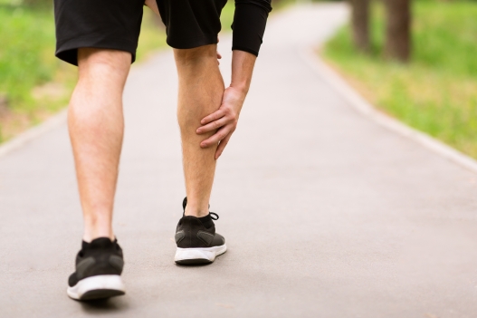 Calf Injury Concept. Closeup back view of sportsman with muscle pain touching his leg, free space