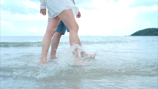 Young couple on vacation on a white sandy beach, clear sky and sea