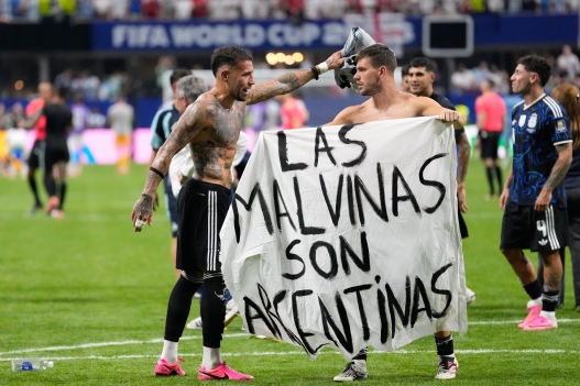 Argentina's Giovani Lo Celso holds a banner with the words "The Malvinas are Argentine", referring to the Falkland Islands, while teammate Argentina's Nicolas Otamendi gestures to him, at the end of the World Cup semifinal soccer match between England and Argentina in Atlanta, Wednesday, July 15, 2026. (AP Photo/Rebecca Blackwell)