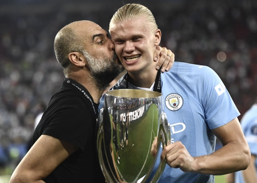 (FILES) Manchester City's Spanish manager Pep Guardiola (L) kisses Manchester City's Norwegian striker #09 Erling Haaland after winning the 2023 UEFA Super Cup football match between Manchester City and Sevilla at the Georgios Karaiskakis Stadium in Piraeus on August 16, 2023. A press release from the club on May 22, 2026 states: "Manchester City can confirm that Pep Guardiola will step down from his role as Manager this summer." (Photo by Spyros BAKALIS / AFP)