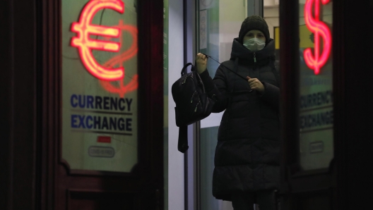 epa09785377 A woman exits between light panels displaying the euro and dollar signs at an exchange office in St. Petersburg, Russia, 25 February 2022. The dollar and the euro are confidently rising on the Moscow and St. Petersburg Exchanges, the ruble accelerated its fall against the dual-currency basket in anticipation of the announcement by Western countries of the previously announced new anti-Russian sanctions. In response to the military operation of the Russian armed forces that began in Ukraine, US authorities imposed sanctions against a number of key Russian banks. The US sanctions list includes VTB, Sberbank, Gazprombank, Sovcombank, Novikombank, Otkritie Bank, Alfa-Bank and Credit Bank of Moscow.  EPA/ANATOLY MALTSEV