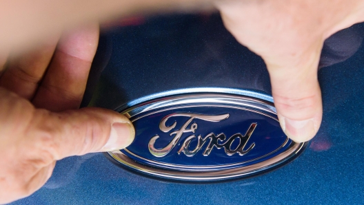 Ein Ford-Mitarbeiter bringt in der Bumper-Vormontage das Ford-Logo an.