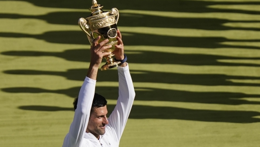 Serbia's Novak Djokovic holds the winners trophy as he celebrates after beating Australia's Nick Kyrgios to win the final of the men's singles on day fourteen of the Wimbledon tennis championships in London, Sunday, July 10, 2022. (AP Photo/Gerald Herbert)