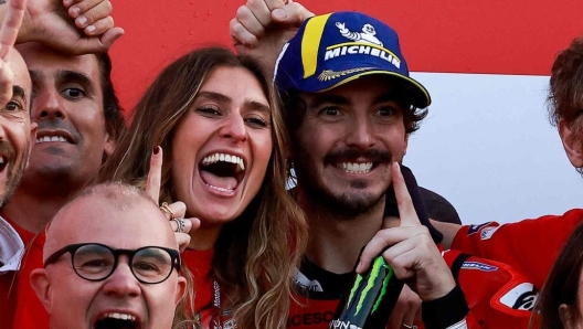 Ducati Italian rider Francesco Bagnaia (C) and his partner Domizia Castagnini (C-L) celebrate with team members after winning the MotoGP Valencia Grand Prix at the Ricardo Tormo racetrack in Cheste, on November 26, 2023. Italy's Francesco Bagnaia enjoyed a dream day as he retained his MotoGP world title and crowned it with victory in the final race of the season in Valencia today. The 26-year-old Ducati rider had been assured of the championship when his sole rival Jorge Martin crashed early in the race. (Photo by JOSE JORDAN / AFP)