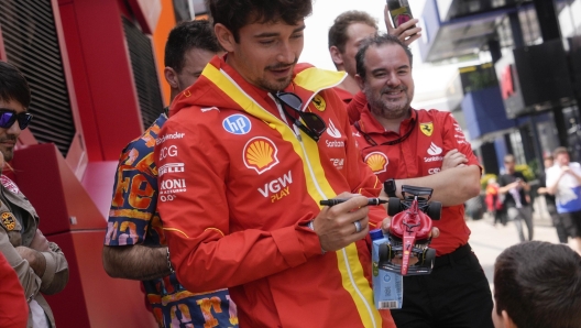 Ferrari driver Charles Leclerc of Monaco signs a Ferrari miniature replica to a child in the paddock of the Dino and Enzo Ferrari racetrack, in Imola, Italy, Thursday, April 16, 2024. The Italy's Emilia Romagna Formula One Grand Prix will be held on Sunday. (AP Photo/Luca Bruno)