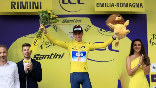 epa11445350 French rider Romain Bardet of Team DSM celebrates on the podium wearing the overall leader's yellow jersey after winning the first stage of the 2024 Tour de France cycling race over 206km from Florence to Rimini, Italy, 29 June 2024.  EPA/GUILLAUME HORCAJUELO