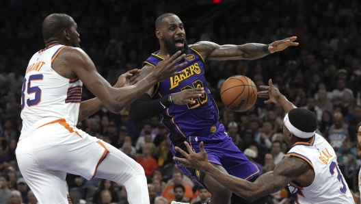 Los Angeles Lakers forward LeBron James loses the ball while driving between Phoenix Suns forward Kevin Durant and guard Bradley Beal