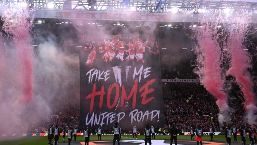 A Manchester United banner is unfurled in the stands as flares explode ahead of the UEFA Europa League semi final second leg football match between Manchester United and Athletic Club Bilbao at Old Trafford stadium in Manchester, north west England, on May 8, 2025. (Photo by Oli SCARFF / AFP)
