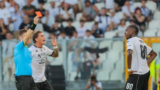 A football referee shows a red card to a player on the field.