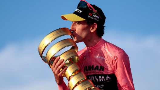 TOPSHOT - Team Visma-Lease a Bike's British rider Simon Yates wearing the pink jersey of overall leader (Maglia Rosa) celebrates holding the Trofeo Senza Fine on the podium after the 21st and last stage and winning the 108th Giro d'Italia cycling race of 143kms from Rome to Rome on June 1, 2025. (Photo by Luca Bettini / AFP)