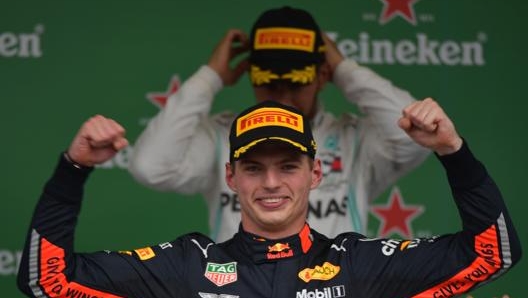 Verstappen raggiante dopo la vittoria. Sullo sfondo Lewis Hamilton. Afp