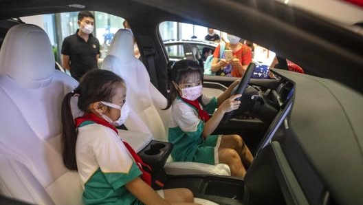 Giovanissime visitatrici di un concessionario Tesla a Guangzhou. Epa