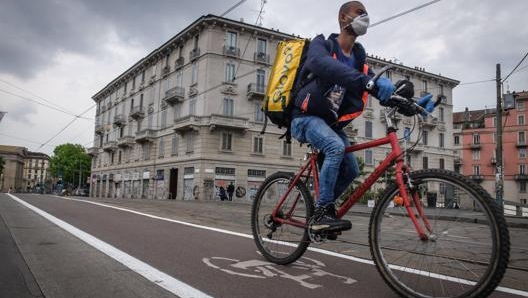 Un fattorino su una ciclabile di Milano. Ansa