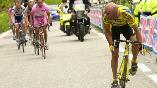 Marco Pantani al Giro nel 2003 davanti a Gilberto Simoni in maglia rosa. Dietro la moto ripresa e il cambio ruote. Ap