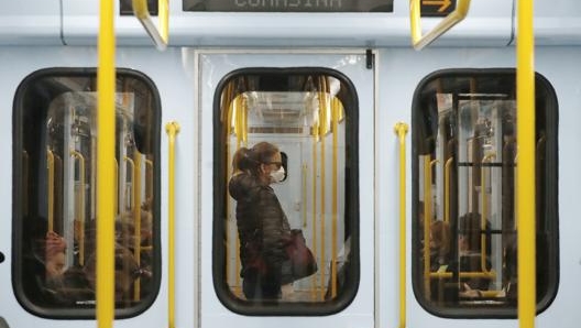 Un vagone della metropolitana di Milano con una donna con la mascherina. LaPresse