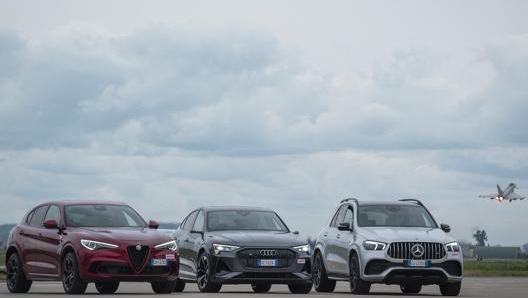 Sullo sfondo l’Eurofighter Typhoon, in primo piano Alfa Romeo Stelvio Quadrifoglio, Audi e-tron S Sportback e Mercedes Gle 53 Coupé