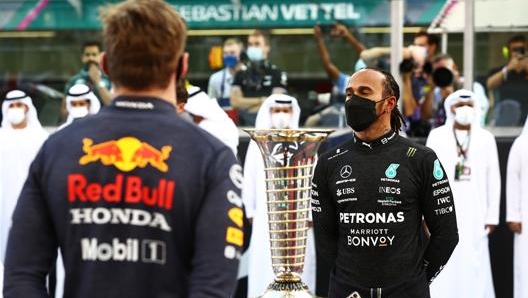 Lewis Hamilton davanti al trofeo iridato e a Max Verstappen ad Abu Dhabi. Getty