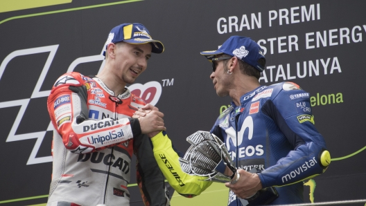 Ducati Team's Spanish rider Jorge Lorenzo (C) celebrates on the podium next to Repsol Honda Team's Spanish rider Marc Marquez (L), second placed, and Movistar Yamaha MotoGP's Italian rider Valentino Rossi (R), third place, after winning the Catalunya MotoGP Grand Prix race at the Catalunya racetrack in Montmelo, near Barcelona on June 17, 2018. / AFP PHOTO / LLUIS GENE