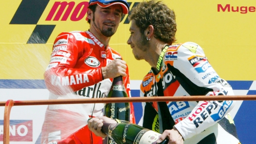 L'italiano Valentino Rossi, festeggia la sua vittoria nella categoria MotoGP, sul Podio, cercando di spruzzare di spumante a Max Biaggi. ANSA/CLAUDIO ONORATI