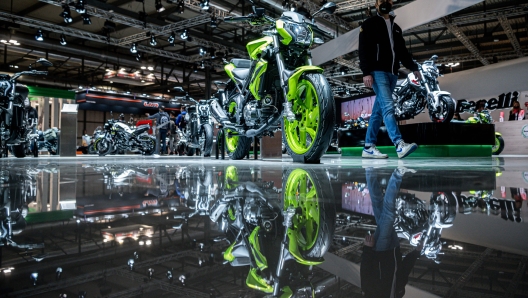 A man walks past a Benelli BN125 motorbike on display on the Benelli stand at EICMA, the 78th edition of the International Bicycle and Motorcycle exhibition during its opening on November 23, 2021 in Milan. (Photo by Piero CRUCIATTI / AFP)